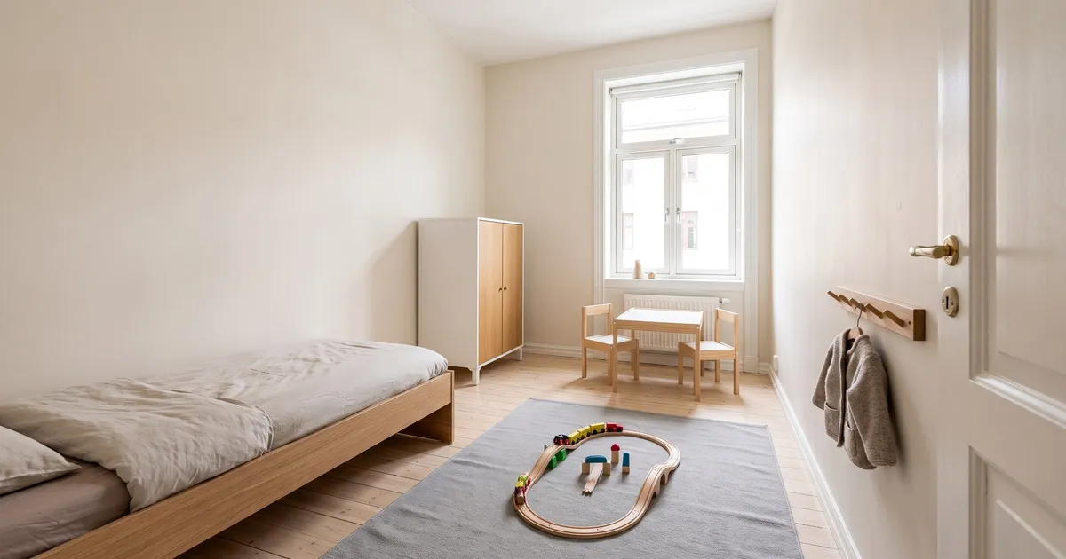 Symbolbild (KI-generiert): kleines Kinderzimmer mit Bodenbett an der Wand, kleinem Schrank, Kindertisch am Fenster, grauem Teppich und Wandgarderobe neben der Tür